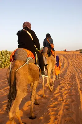 a group of people riding camels in the desert at Diament Luxury Camp-Sahara Desert Experience in Merzouga in Merzouga