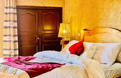 a bedroom with a bed with red and white pillows at Hotel Camping Les Roses Des Dunes & Piscine in Merzouga
