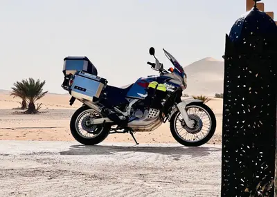 a motorcycle parked in the sand in the desert at Hotel Camping Les Roses Des Dunes & Piscine in Merzouga
