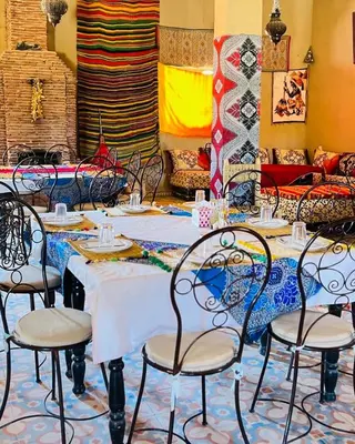 a dining room with tables and chairs at Hotel Camping Les Roses Des Dunes & Piscine in Merzouga