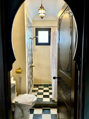 a bathroom with a toilet and a door at Riad Timskrine in Ourika
