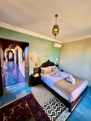 a bedroom with a large bed and a chandelier at Riad Timskrine in Ourika
