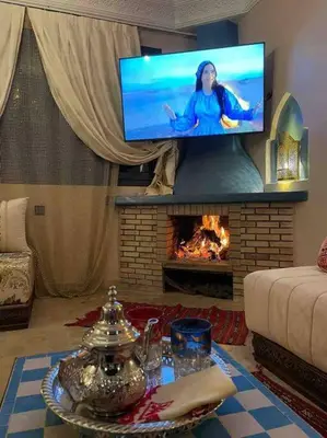 a living room with a fireplace with a tv above it at Riad Timskrine in Ourika