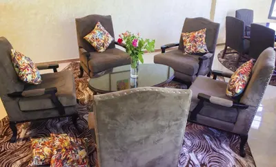 a room with chairs and a table with a vase of flowers at Hôtel La Chambotte in Imouzzer Kandar