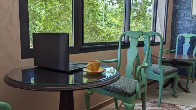 a table and chairs with a laptop on it at Hôtel La Chambotte in Imouzzer Kandar
