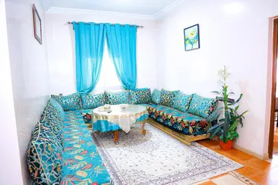 a living room with a blue couch and a table at Cozy Host House with 2 air conditioned rooms in Er Rachidia