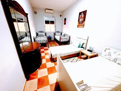 a room with two beds and a checkered floor at Cozy Host House with 2 air conditioned rooms in Er Rachidia