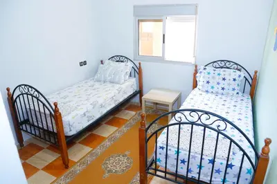 a bedroom with two beds and a window at Cozy Host House with 2 air conditioned rooms in Er Rachidia
