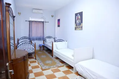 a bedroom with two beds and a table and chairs at Cozy Host House with 2 air conditioned rooms in Er Rachidia