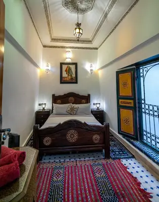 a bedroom with a bed and a red rug at Riad Fes Allouch in Fès