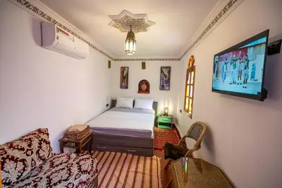 a bedroom with a bed and a flat screen tv at Riad Fes Allouch in Fès