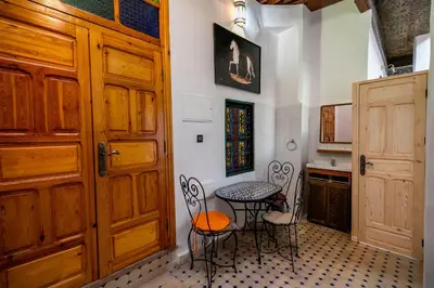 a kitchen with a table and chairs next to a door at Riad Fes Allouch in Fès