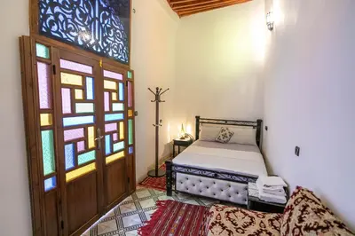 a bedroom with a bed and a stained glass window at Riad Fes Allouch in Fès