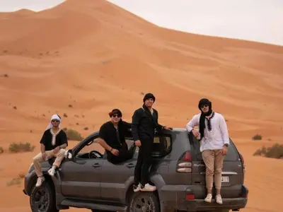 a group of men sitting on the back of a truck in the desert at lecherif luxury Camps in Merzouga