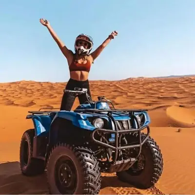 a woman standing on a fourwheeler in the desert at lecherif luxury Camps in Merzouga