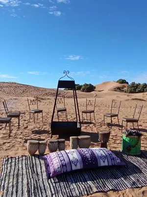 a beach with chairs and a swing in the sand at lecherif luxury Camps in Merzouga