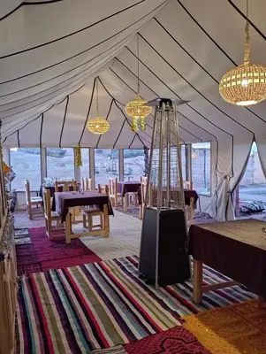 a tent with tables and chairs and chandeliers at lecherif luxury Camps in Merzouga