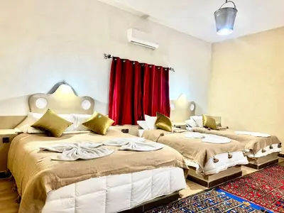 two beds in a room with a red curtain at Hotel le Touareg in Merzouga
