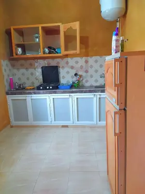 a kitchen with white cabinets and a tv in it at Luxury apartment Hassilabied Merzouga in Hassilabied