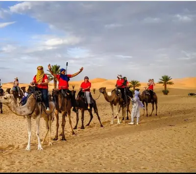 a group of people riding on camels in the desert at Merzouga Comfortable Camps in Merzouga
