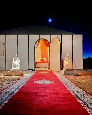 a bedroom with a red carpet in a tent at Merzouga Comfortable Camps in Merzouga