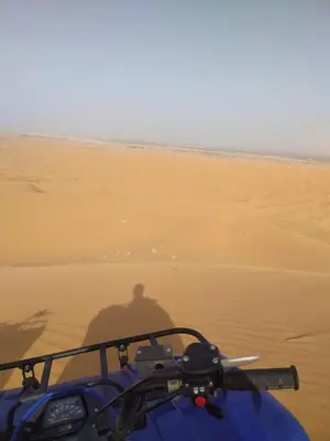 a shadow of a person riding a motorcycle in the desert at Merzouga Comfortable Camps in Merzouga