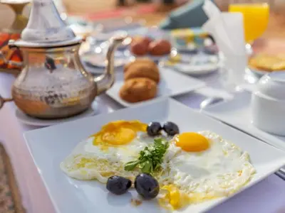 a plate of eggs and blueberries on a table at Merzouga Comfortable Camps in Merzouga