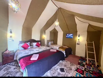 a bedroom with two beds and a ladder in a room at Merzouga Comfortable Camps in Merzouga
