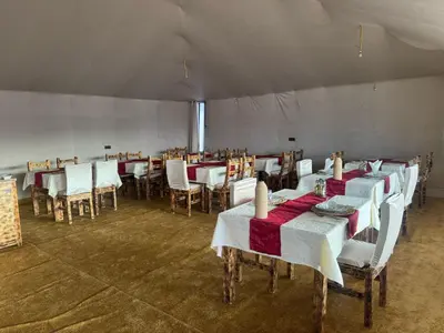 a dining room with tables and chairs in a tent at Merzouga Comfortable Camps in Merzouga