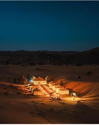 a group of buildings in the desert at night at Merzouga Comfortable Camps in Merzouga