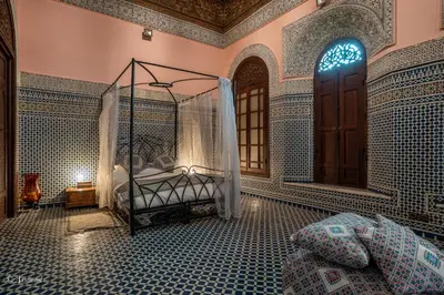 a bedroom with a bed in a room with blue tiled walls at Riad Fes Palacete in Fès