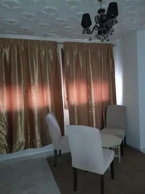 a room with two chairs and a table and curtains at superbe appartement bien placé in Fès