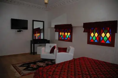a bedroom with a bed and chairs and stained glass windows at Collier De La Colombe in Meknès