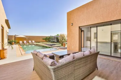 a living room with a couch and a pool at Villa Sakina, piscine Chauffée, ping-pong, cuisinière in Marrakech