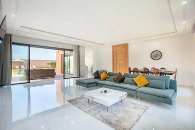a living room with a blue couch and a table at Villa Sakina, piscine Chauffée, ping-pong, cuisinière in Marrakech