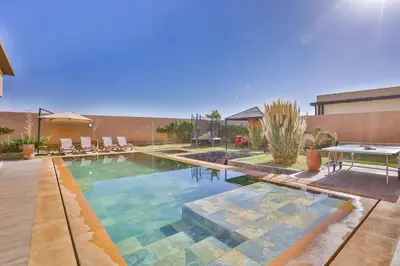a pool with a table and chairs in a backyard at Villa Sakina, piscine Chauffée, ping-pong, cuisinière in Marrakech