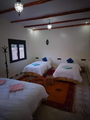 a room with three beds and a table in it at Hotel AZUL Todra Gorges in Tinerhir