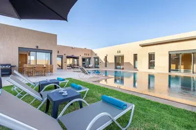 a pool with chairs and tables next to a building at Villa Kassia , Jacuzzi, Hamman, jeux… in Marrakech