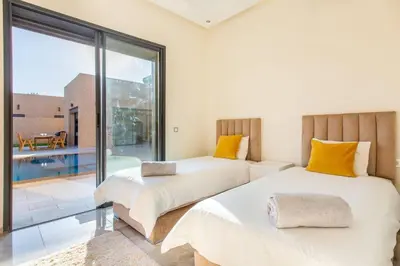 two beds in a room with a large window at Villa Kassia , Jacuzzi, Hamman, jeux… in Marrakech