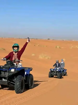 two people riding on atvs in the desert at Riad Berber Merzouga in Merzouga