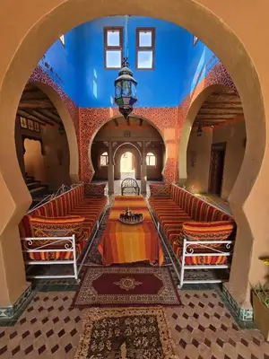 an empty room with orange chairs and a blue ceiling at Riad Berber Merzouga in Merzouga