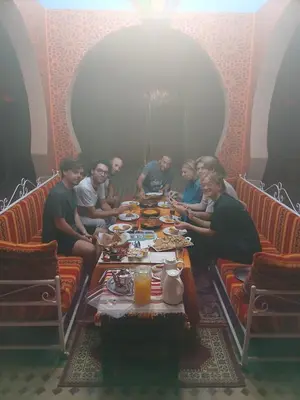 a group of people sitting around a table eating food at Riad Berber Merzouga in Merzouga