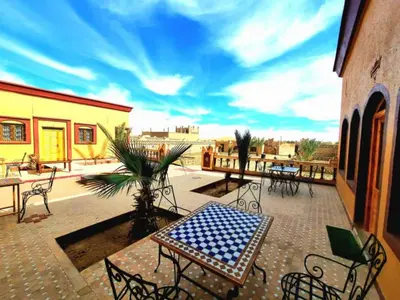 a patio with a table and chairs on a balcony at Riad Berber Merzouga in Merzouga