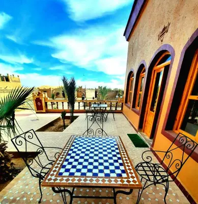 a checkered table and chairs on a patio at Riad Berber Merzouga in Merzouga