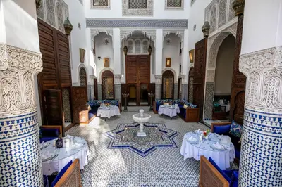 a room with tables and chairs in a building at Riad Fes Ziyat & Spa in Fès