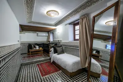 a room with a bed and a couch and a mirror at Riad Fes Ziyat & Spa in Fès