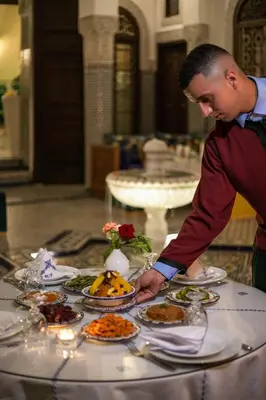 a man standing at a table with plates of food at Riad Fes Ziyat & Spa in Fès