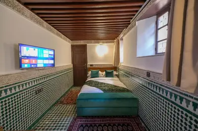 a bedroom with a bed and a flat screen tv at Riad Fes Ziyat & Spa in Fès