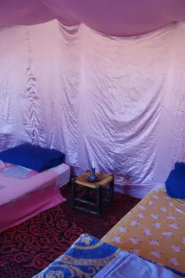 a room with two beds and a table at Sahara Berber Camp - Mhamid Discovery Camp in Mhamid El Ghizlane