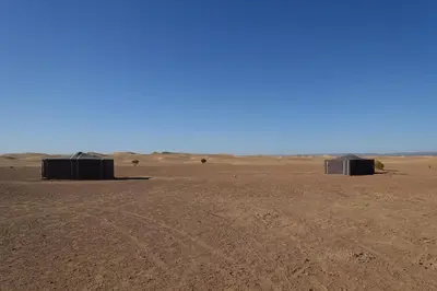 two tents in a desert with a blue sky at Sahara Berber Camp - Mhamid Discovery Camp in Mhamid El Ghizlane